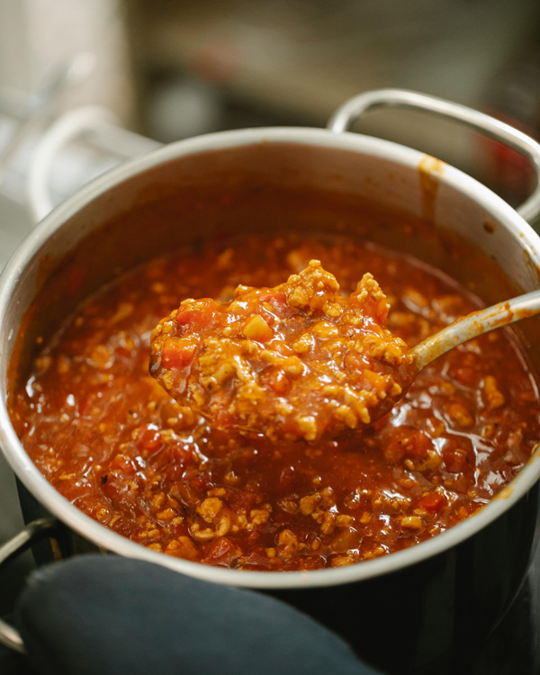 Une louche puise dans une casserole de ragù