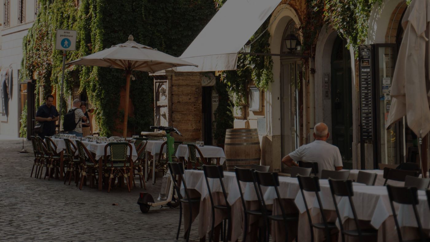 Tables dressées sur une rue pavée, sous les parasols