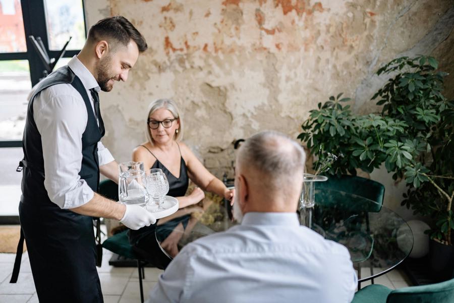 Un serveur dépose des verres sur la table de deux convives