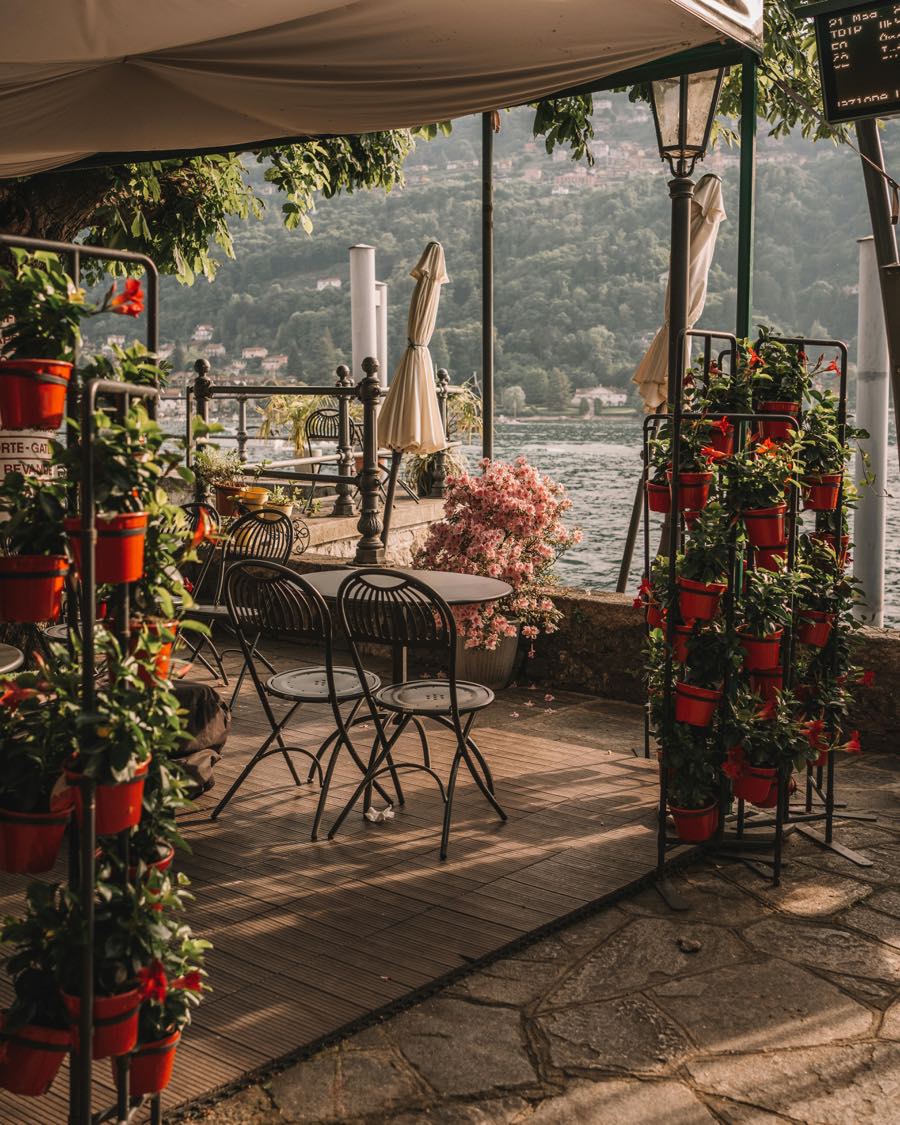 Terrasse ombragée avec pots de fleurs rouges au bord de l'eau