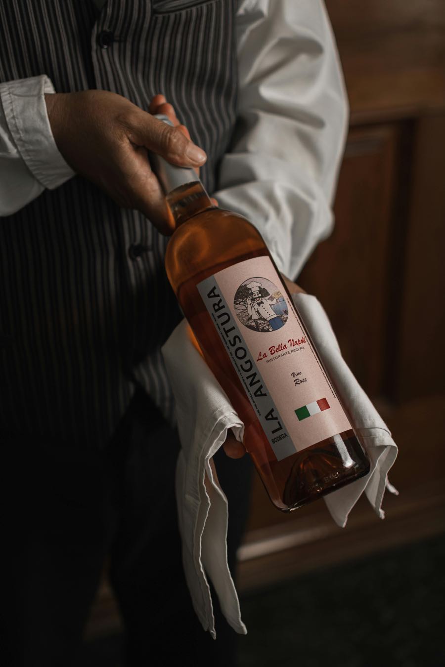 Un serveur présente une bouteille de rosé italien dans un linge blanc